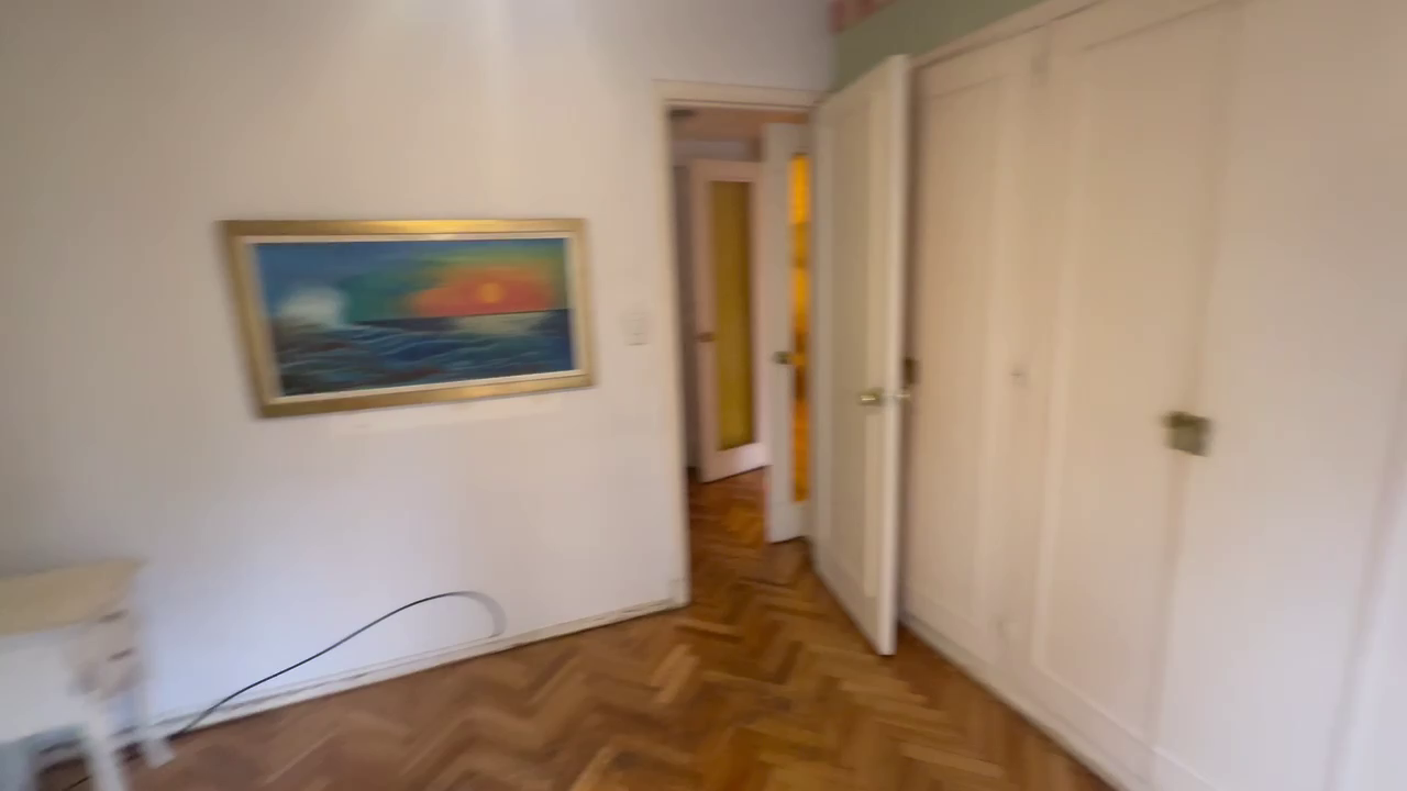 Master bedroom with parquet floor and a wall of built-in white closets