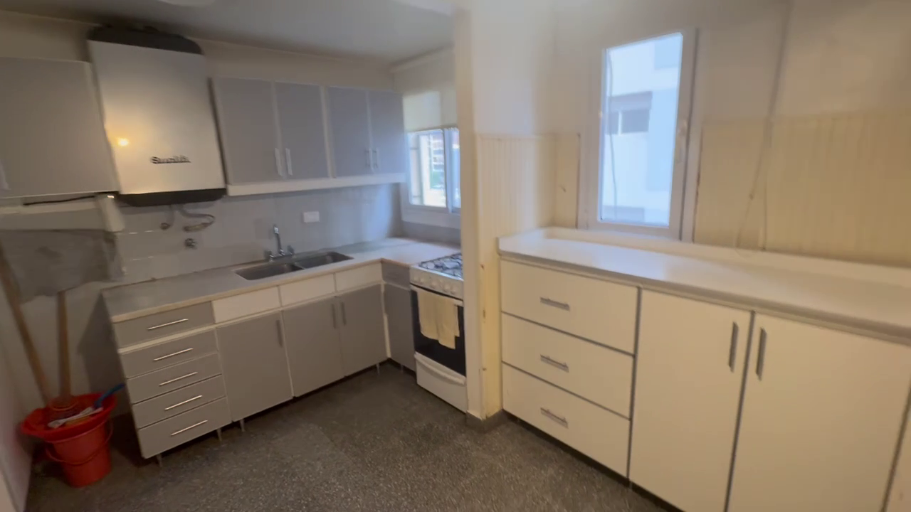 Apartment kitchen with white cabinets, gas stove, and white walls