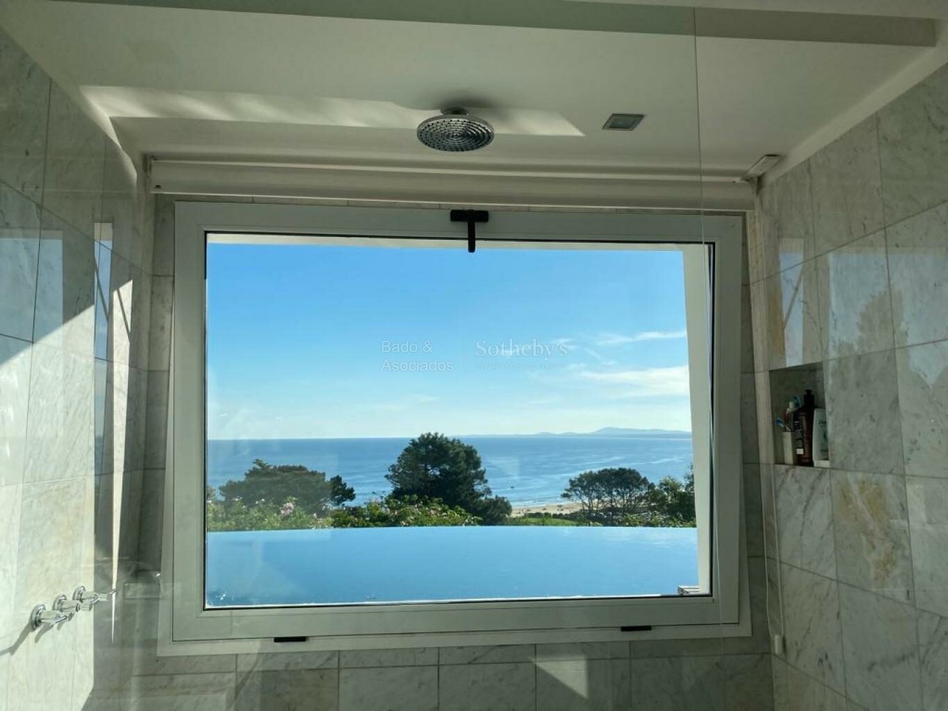 Bathroom with a large window framing the ocean and sky