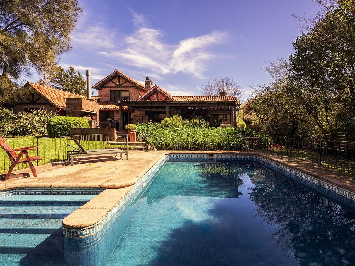 Swimming pool with the house behind it and loungers on the deck