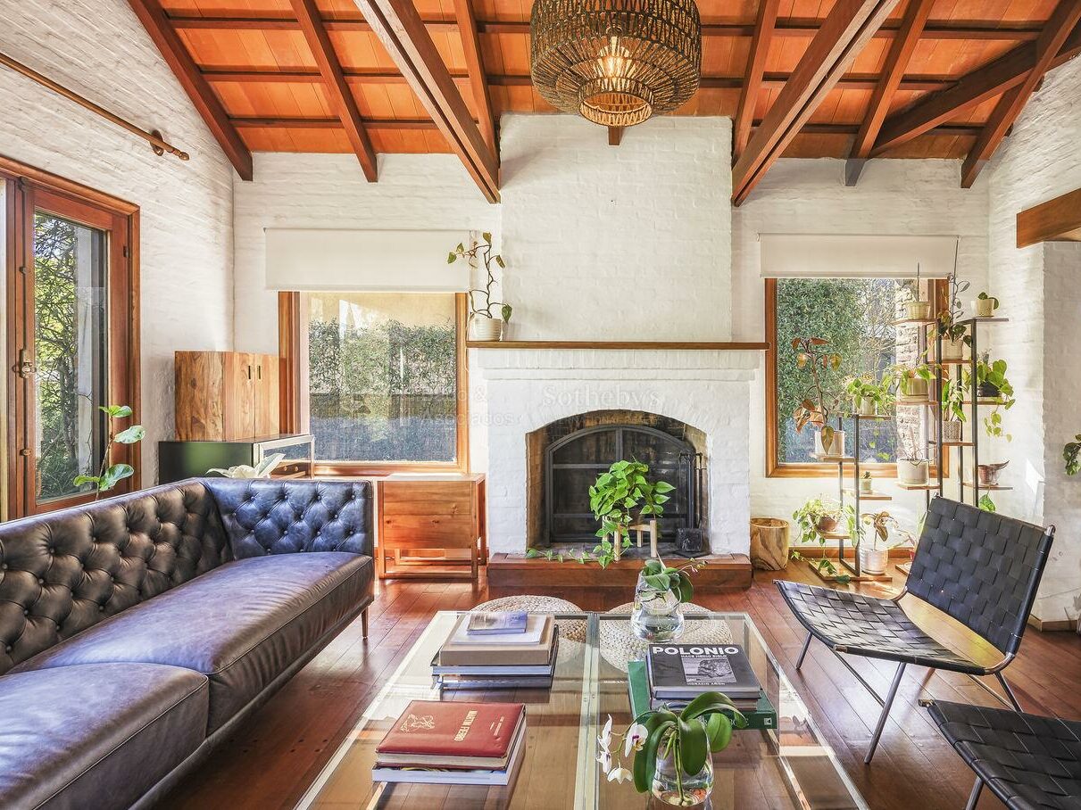 Living room under an exposed timber ceiling with a stone fireplace
