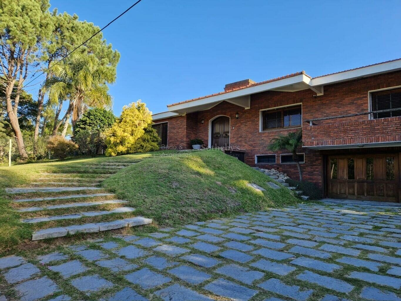 Brick exterior of the El Pinar house above a sloping lawn and stone steps