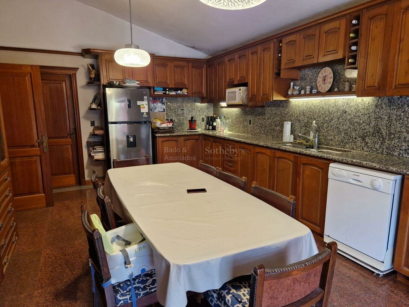 Kitchen with dark cabinetry, stone counters and a dining table