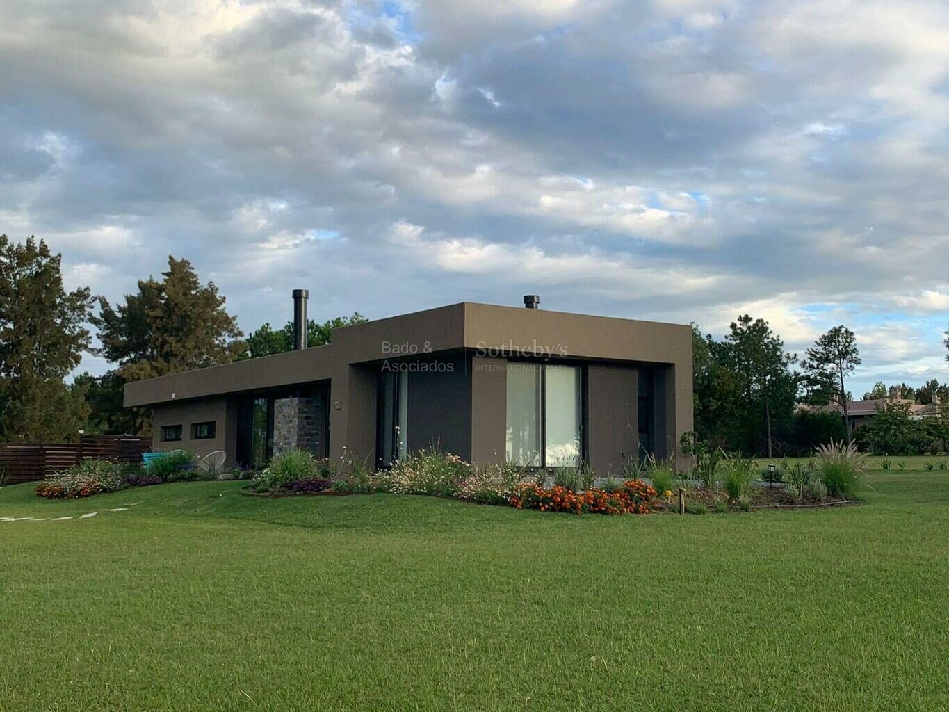 Single-storey contemporary house with a wide lawn and planted borders at El Quijote