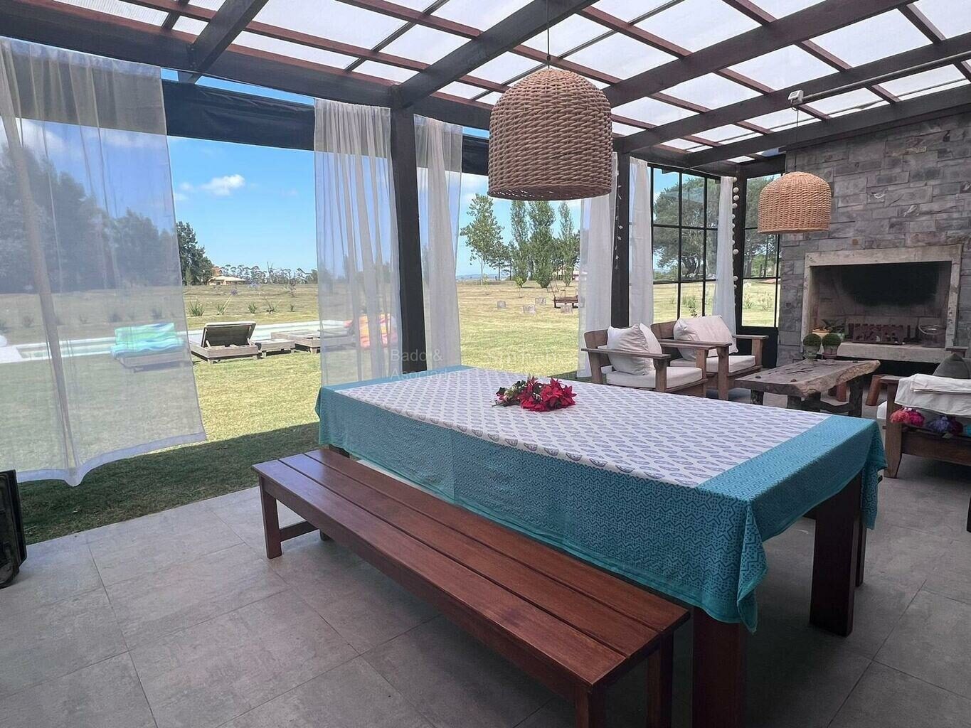 Covered outdoor dining area with a table and a stone fireplace