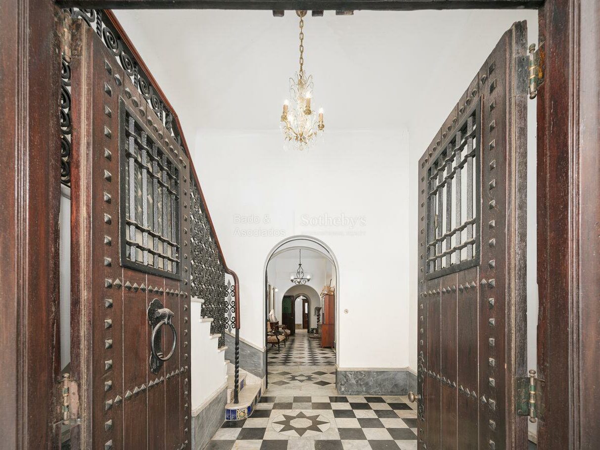 Entrance doors opening into a hall with black and white checkerboard flooring