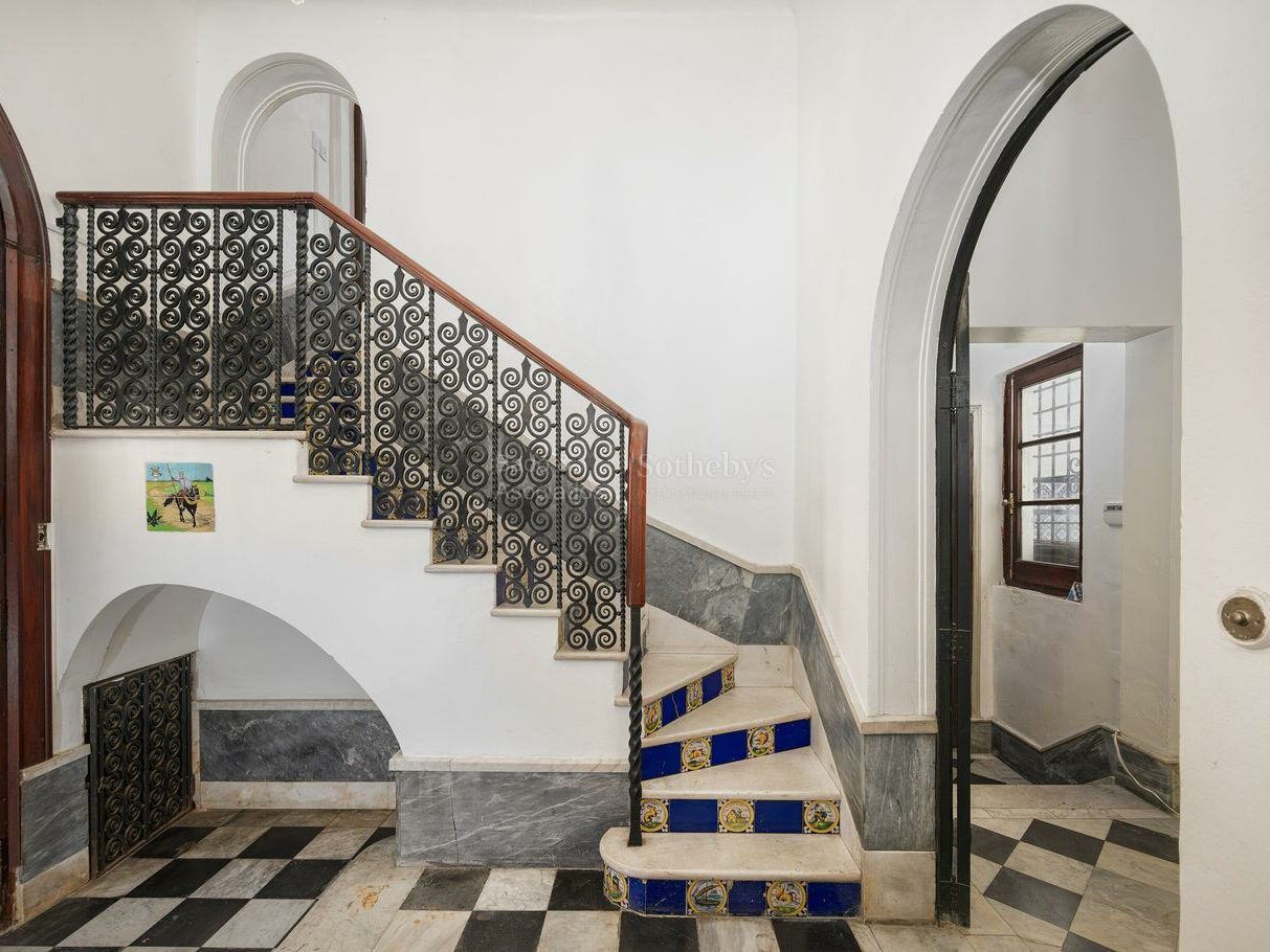 Staircase with tiled steps, wrought iron balustrade and checkerboard floor