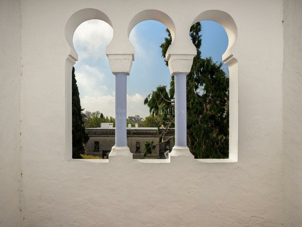 Horseshoe arches of the villa's rooftop lookout with a garden view