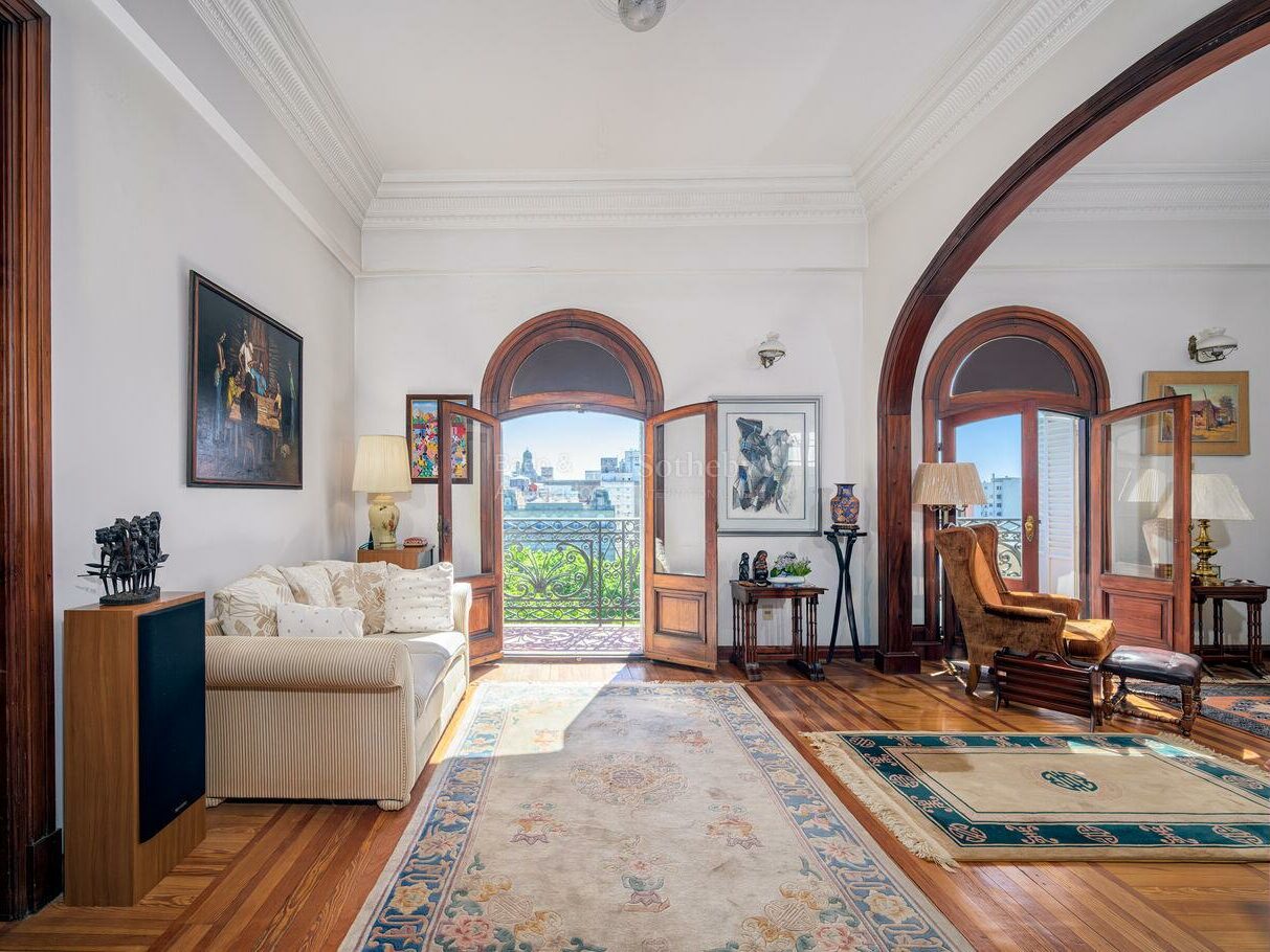 Reception room of the Palacio Montero apartment with high ornamental ceilings and arched doors opening to the balcony