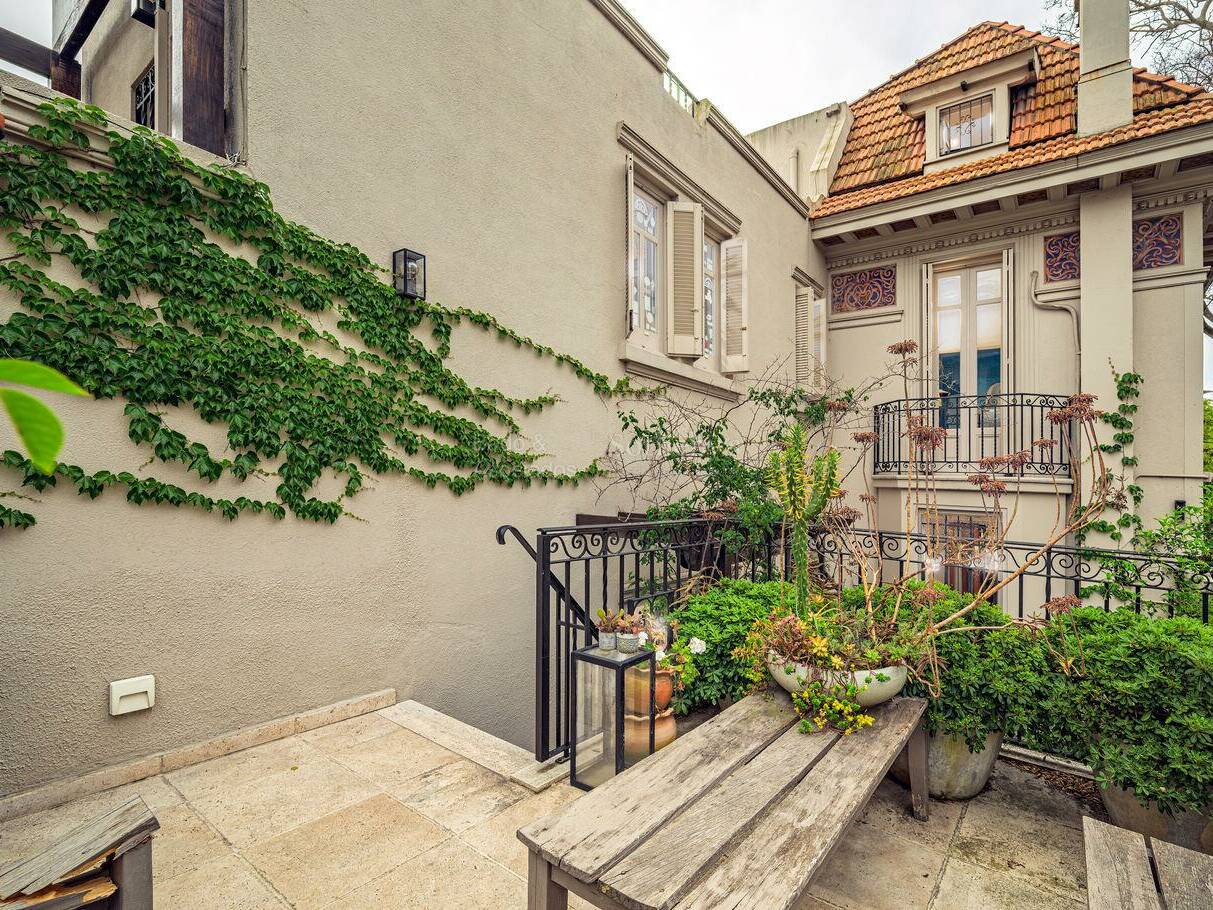 Planted outdoor area with a stone bench and steps at the Pocitos period house